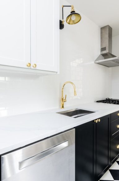 Cuisine moderne avec plan de travail blanc, évier noir et appareils en acier inoxydable.