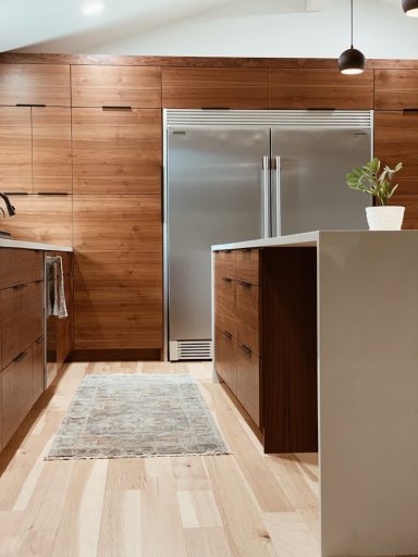 Cuisine moderne avec des armoires en bois et un réfrigérateur argenté. Plante sur le plan de travail.