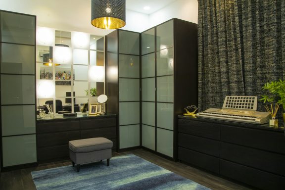 Chambre moderne avec des meubles sombres, éclairage doux et un coin bureau.