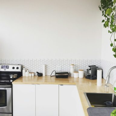 Cuisine moderne avec plan de travail en bois, appareils en inox et plantes suspendues.