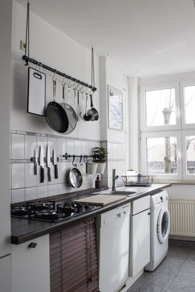 Cuisine moderne avec ustensiles suspendus et un lave-linge intégré.