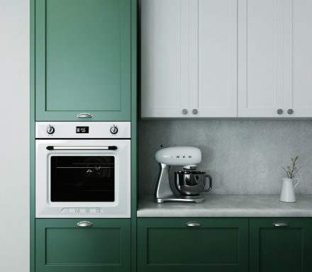 Cuisine moderne avec des meubles verts et blancs, four intégré et mixeur sur le plan de travail.