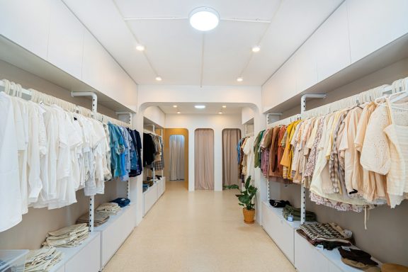 Boutique de vêtements avec des étagères remplies de vêtements colorés.