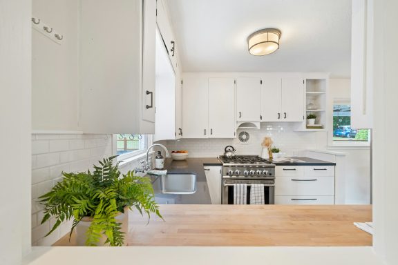 Cuisine moderne avec des armoires blanches, four en acier inoxydable et plantes décoratives.